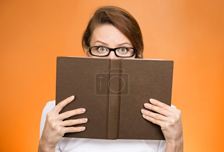 Woman with glasses hiding her face behind book