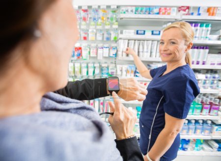 Customer Showing Smartwatch To Mature Pharmacist