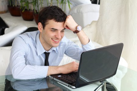 Smiling men think and work at the laptop