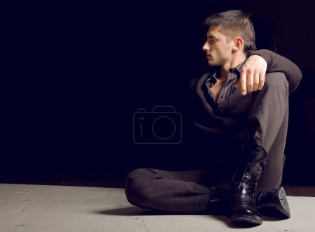 Stylish young man sitting on a floor