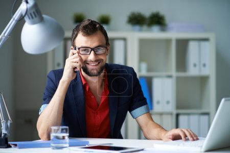 Businessman speaking on the phone and working with laptop