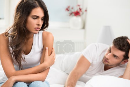 Unhappy young couple in bedroom
