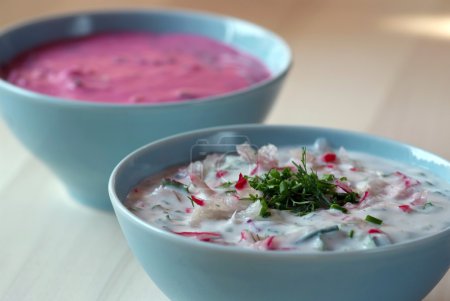 Chłodnik - cold beetroot soup in a bowl on a wooden table.