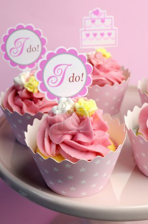 Pink wedding cupcakes with I Do topper signs - close up with bokeh vertical.