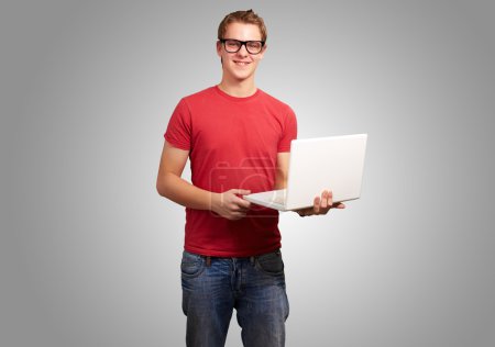 portrait of young student man holding laptop over grey backgroun