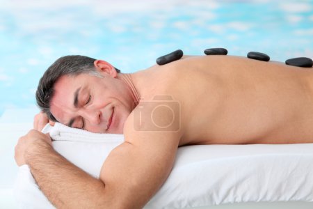 Man laying on massage bed with hot stones