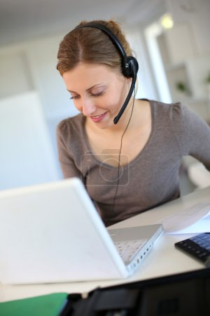 Young woman working from home with laptop and headset