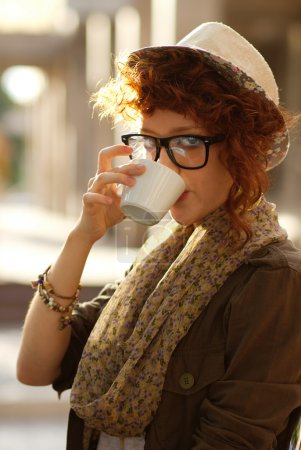 Hipster girl drinking coffee outdoors
