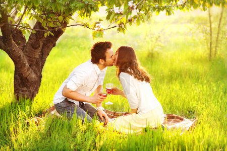 Couple in love kissing in nature are holding wine glasses