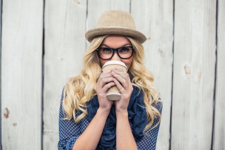 Smiling fashionable blonde drinking coffee outdoors