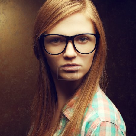 Portrait of a young beautiful red-haired wearing trendy glasses