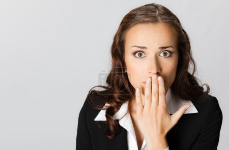 Business woman covering with hands her mouth, over grey
