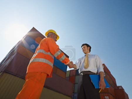 Businessman and manual worker with cargo containers
