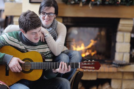 Young romantic couple sitting and relaxing in front of fireplace at home