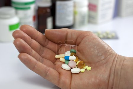 Pills in hand against medicines in pharmacy