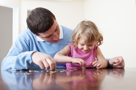 Dad and daughter puts coins