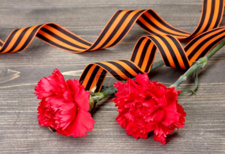 Carnations and St. George's ribbon on grey wooden background