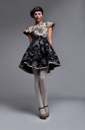Supermodel fashionable brunette standing in grey dress