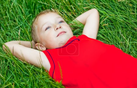 Pensive child day dreaming in fresh grass