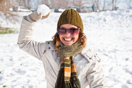 Happy young woman playing snowball fight