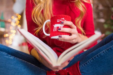 Woman reading book with hot drink