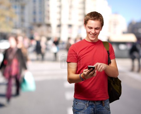 Portrait of young man touching mobile screen at crowded street