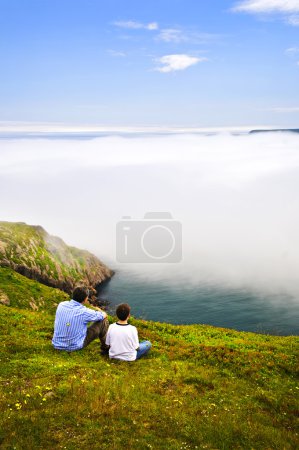 Father and son looking at foggy ocean view in Newfoundland