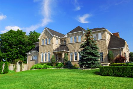 Large upscale residential home with bright green lawn and blue sky