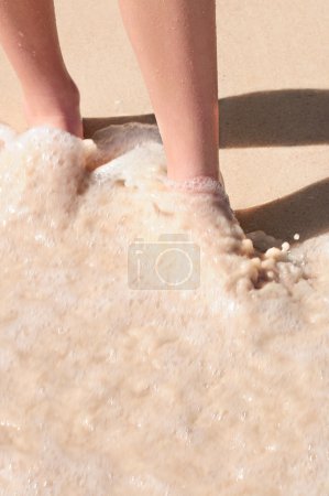 Feet washed in surf on tropical sandy beach