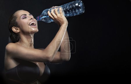 Young beauty drinking bottled mineral water