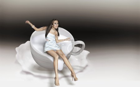 Dynamic photo of a young beauty in a cup of cappuccino
