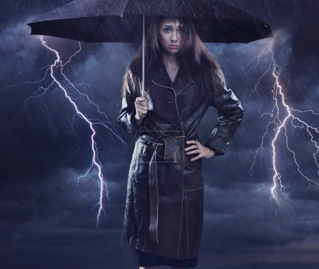 Single woman wearing coat holding umbrella. Creative szmbol of t