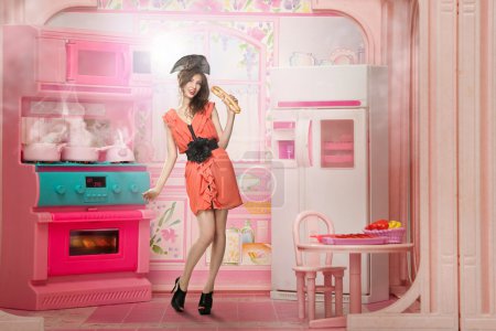 Young woman like a doll cokking in pink kitchen