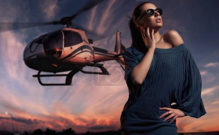 Fashionable lady wearing sunglasses with helicopter in the background