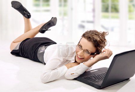 Happy young businesswoman with laptop on the floor