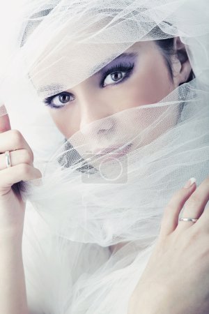 Young brunette beauty or bride, behind a white veil