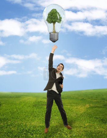 Businessman reaching green energy symbol