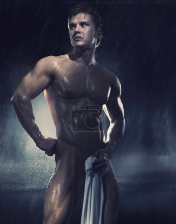 Young handsome athlete standing in the rain
