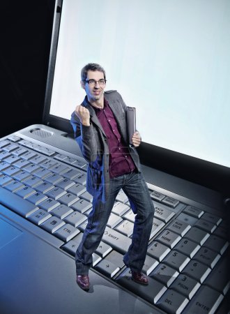 Conceptual photo of a happy man standing on the laptop's keyboar