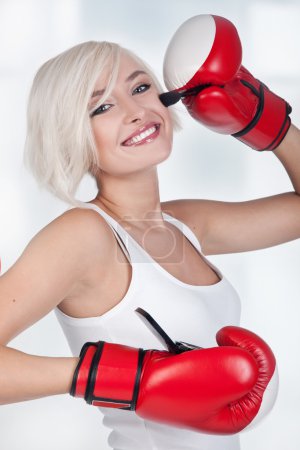 Young beauty doing make up in boxing gloves
