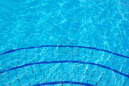 Blue background with sun reflected in the swimming-pool water