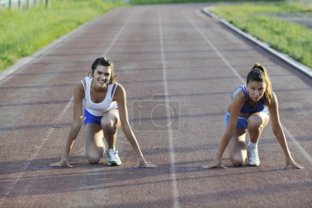 Two girls running on athletic race track