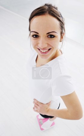 Happy diet concept with young woman on pink scale