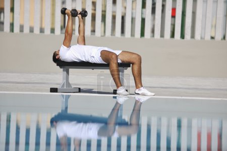 Young healthy athlete man exercise at poolside