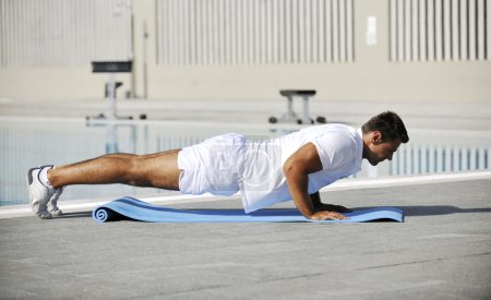 Young healthy athlete man exercise at poolside