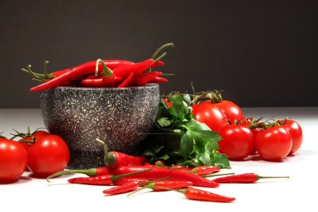 Red peppers and tomatoes with ganite bowl on dark