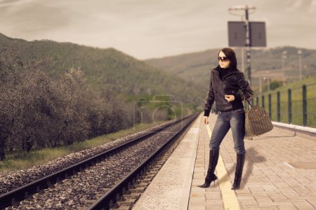 Photo of young woman waiting at the train station for its train