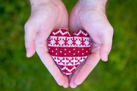 Man hands with red knitted heart