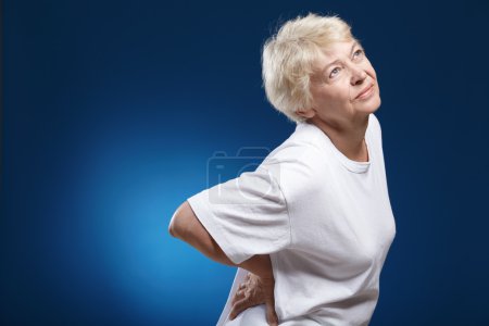 An elderly woman with a sick back on a blue background