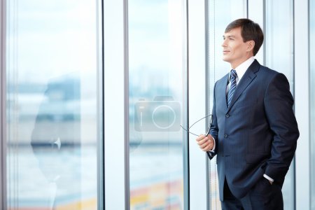 A man in a business suit looks out the window